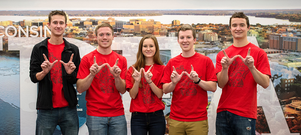 Four UW students showing the 'W' sign with their hands