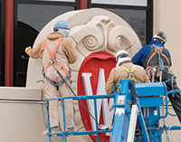Workers mount the University of Wisconsin crest onto Grainger Hall