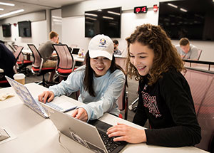 Two female students work on their laptops in the WSB Learning Commons