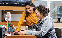Roommates Jaqueline Sanchez and Hannah Brennan look at a laptop